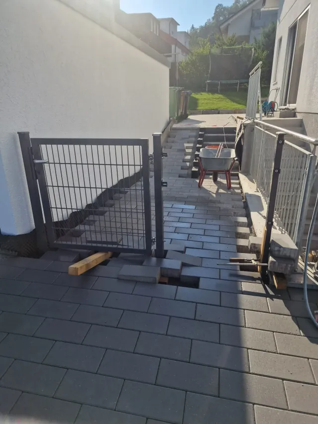 Dunkel gepflasterte Zufahrt mit Tor neben dem Haus